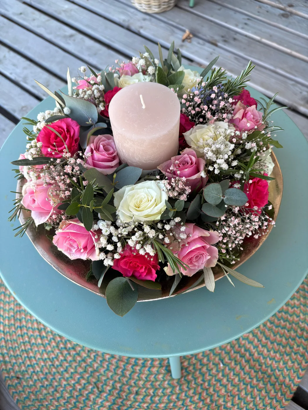 Tischkranz aus Rosen, Schleierkraut und Eukalyptus mit Kerze auf goldenem Teller