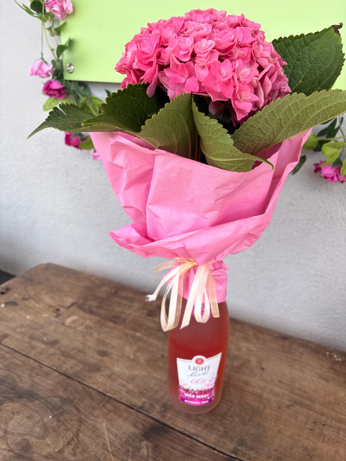 Rosa Hortensie als Geschenk verpackt mit kleiner Flasche