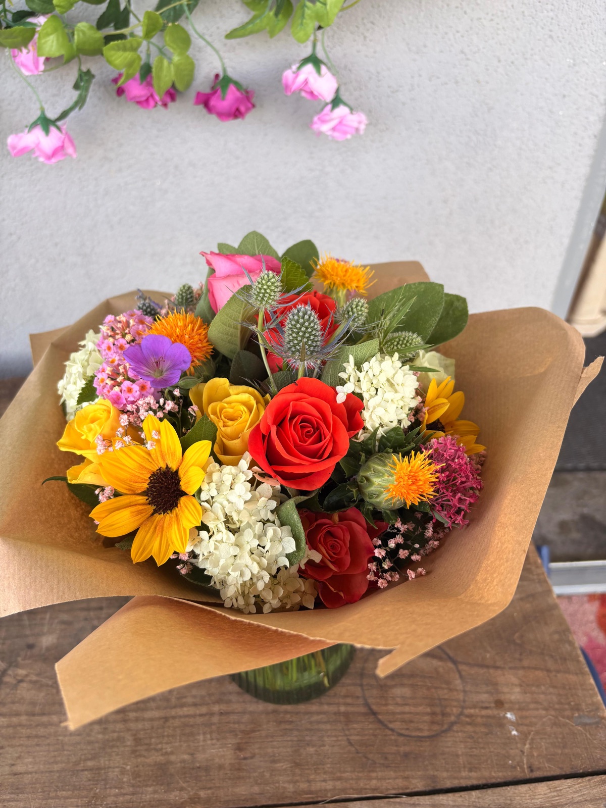 Bunter Sommerstrauß mit Sonnenblumen, Rosen und Disteln in Kraftpapier