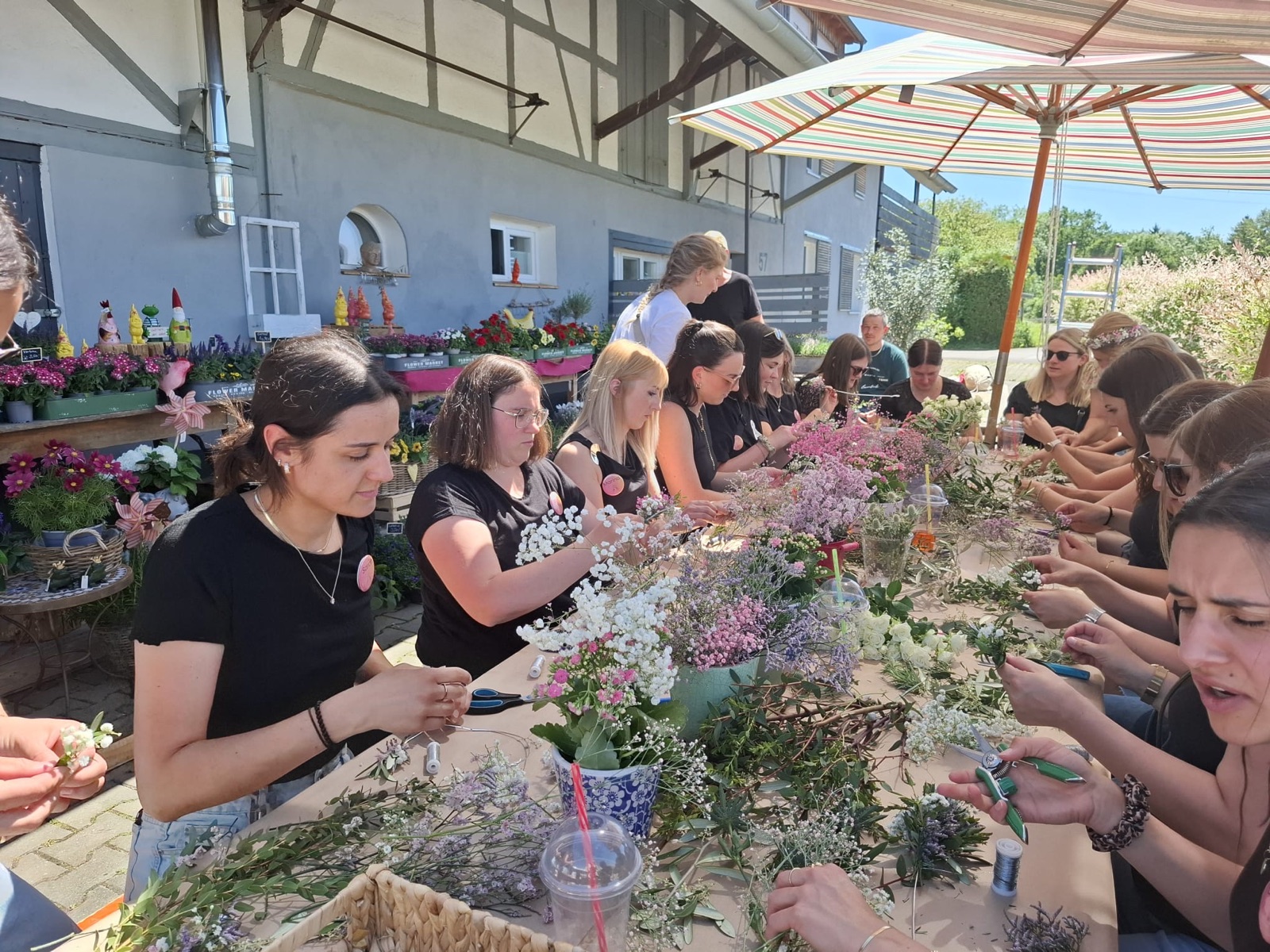 Gruppe bindet Blumenkränze beim Junggesellinnenabschied vor dem Blumenladen